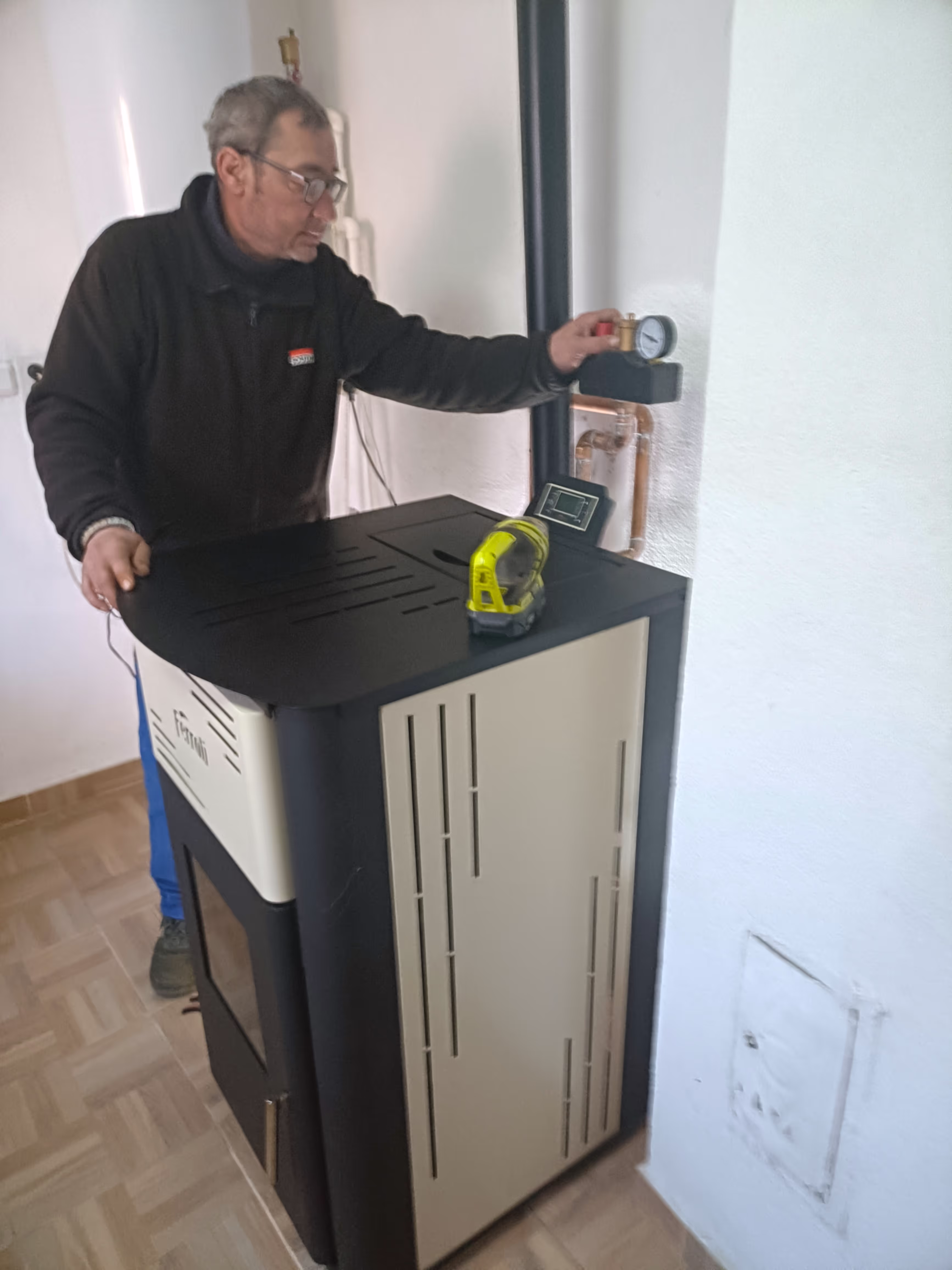 A technician adjusting the pressure gauge on a Ferroli heating stove during installation or maintenance.